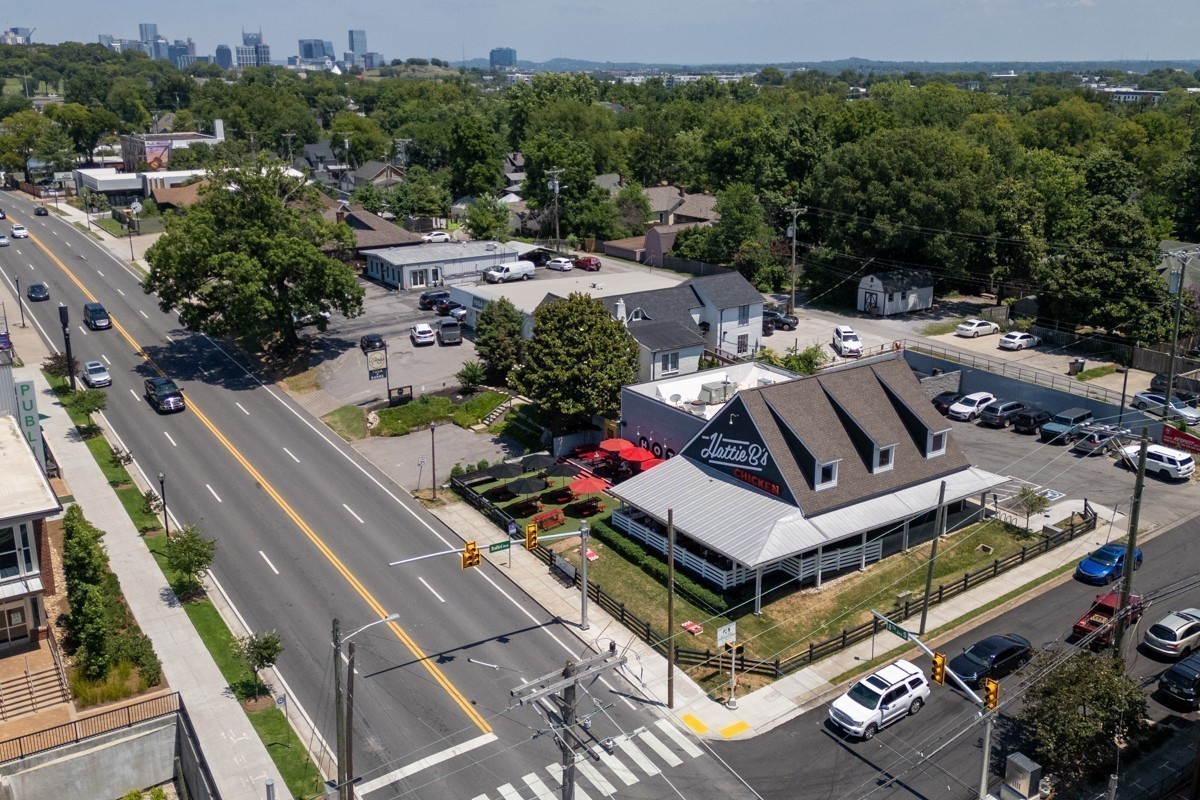 Aerial view of Hattie B’s Chicken, surrounding streets, and Nashville’s downtown skyline.