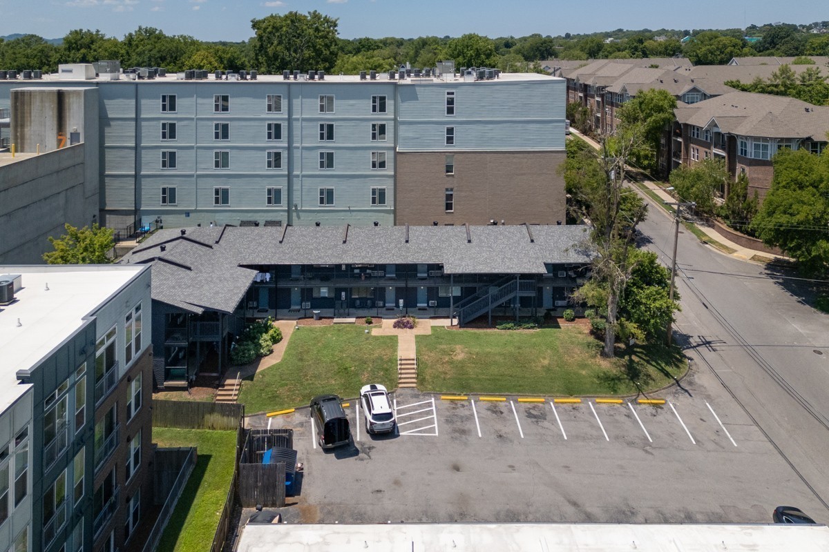 Aerial view of a residential complex with a courtyard, parking lot, and surrounding trees.