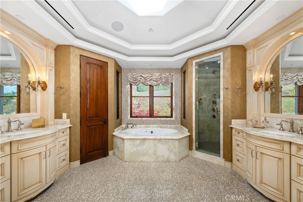 Primary bathroom with corner soaking tub, glass shower, and matching cream vanities.