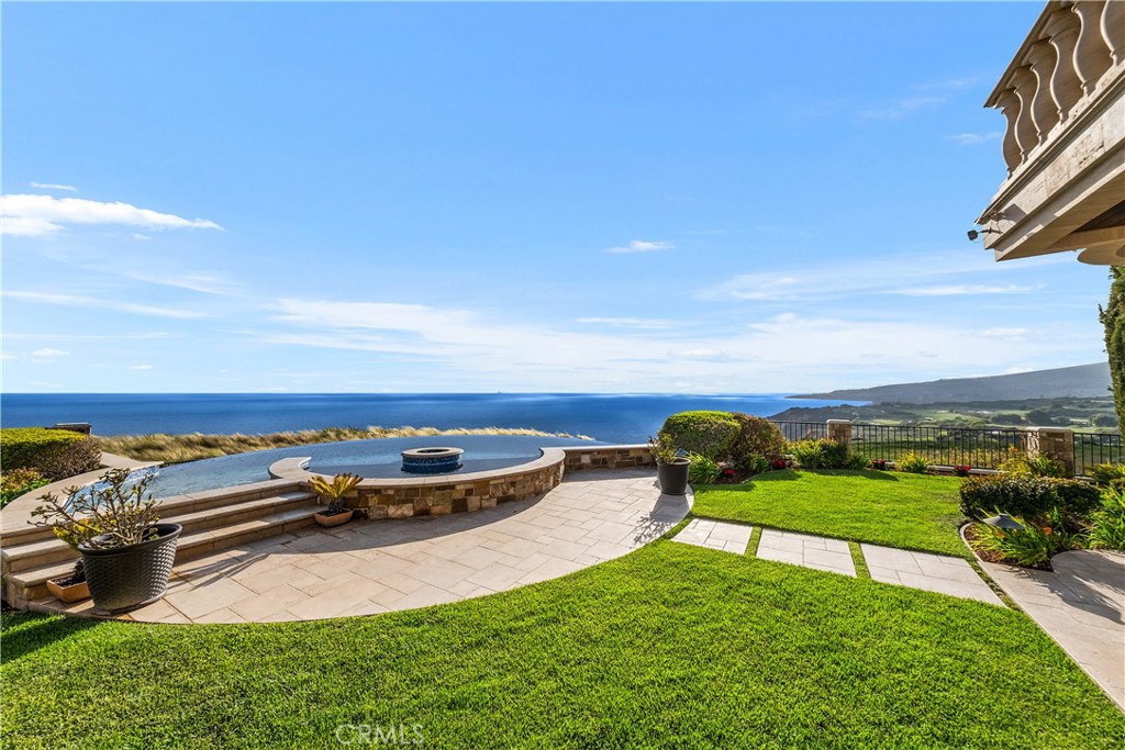 Oceanfront backyard with a curved pool, stone patio, and expansive coastal views.