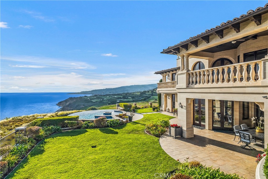 Coastal home with stone balconies, a swimming pool, and ocean views.