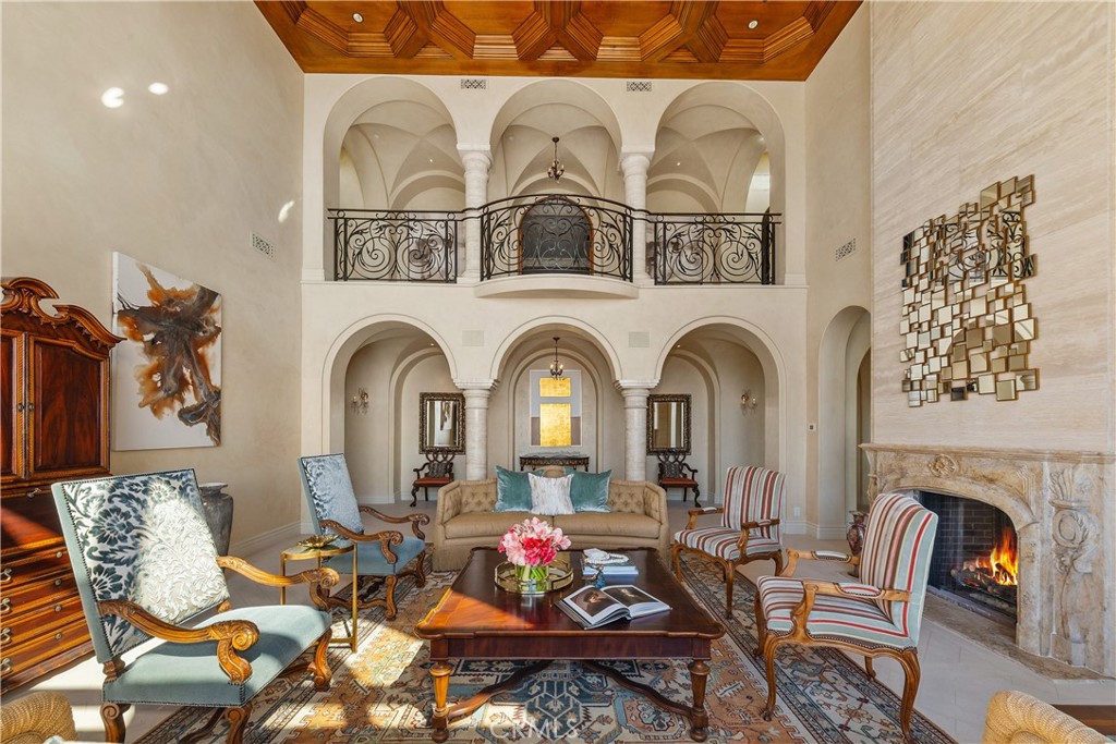 Formal living room with an arched balcony, carved wood ceiling, and stone fireplace.