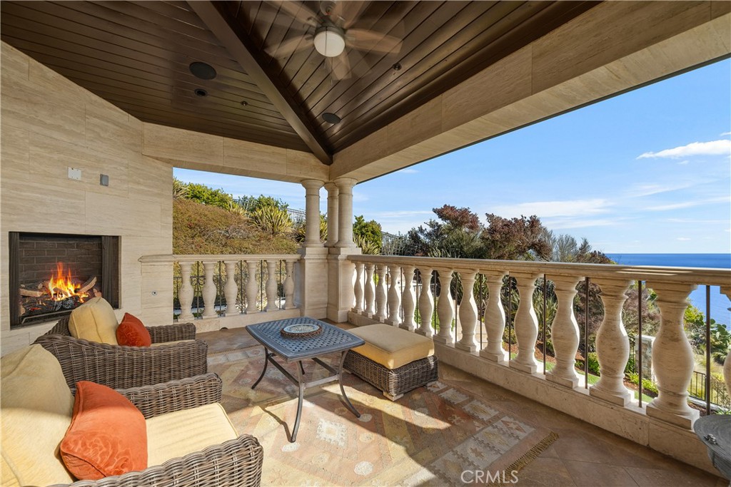 Covered patio with a stone fireplace, wicker seating, and an ocean view.