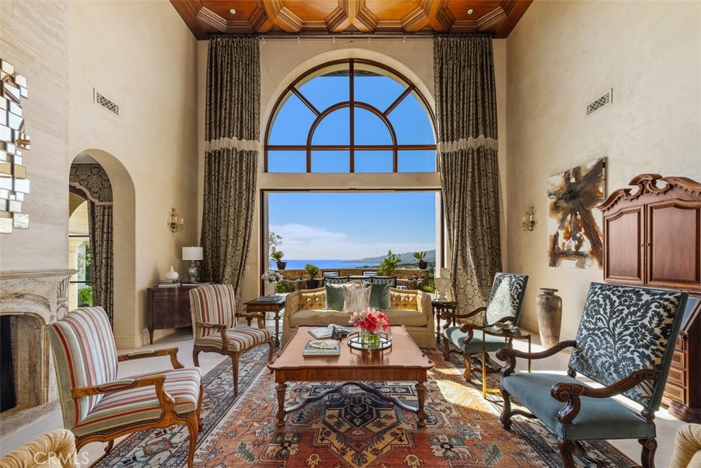Living room with a coffered wood ceiling, arched window, and ocean view.
