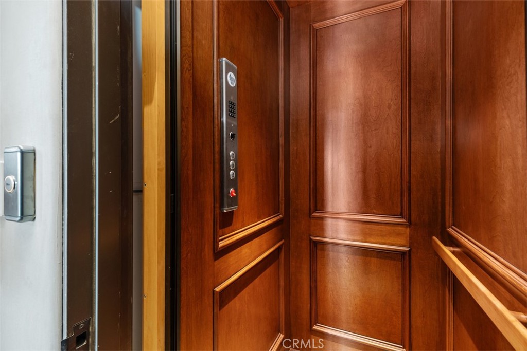 Wood-paneled elevator interior with a metal control panel and wooden handrail.