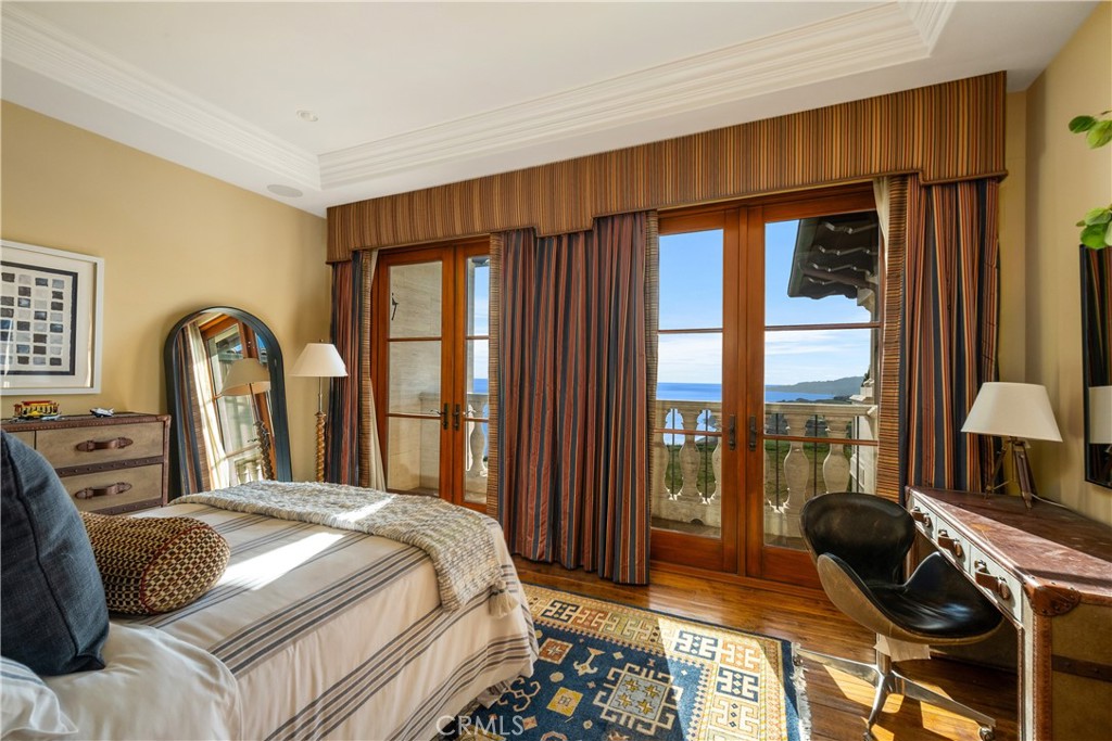 Bedroom with ocean views through wood-framed glass doors and striped curtains.