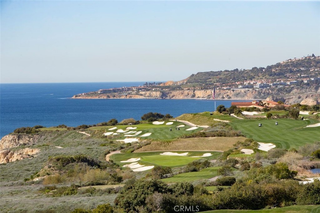 Coastal golf course overlooking the Pacific Ocean, with cliffside homes in the distance.