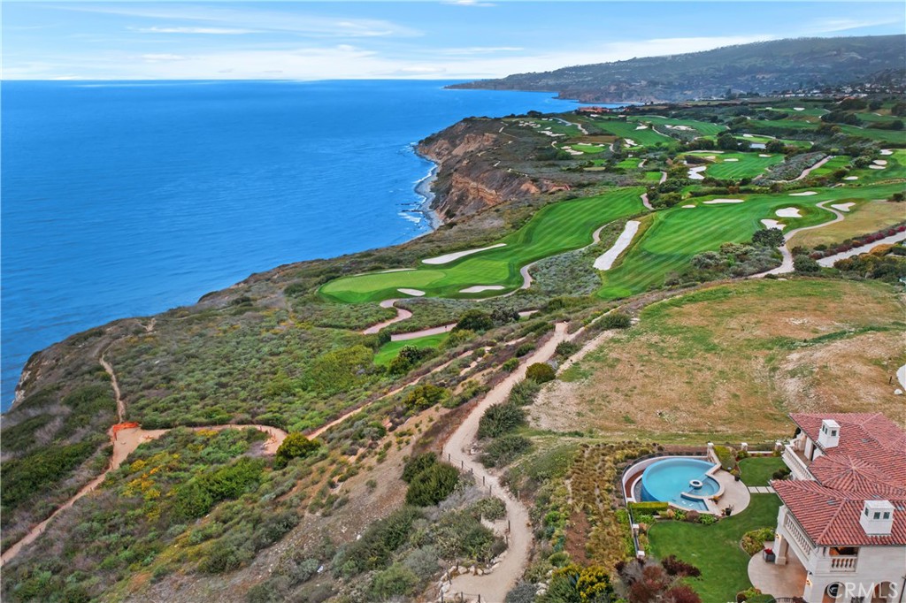 Coastal golf course and ocean beside a home with a swimming pool.