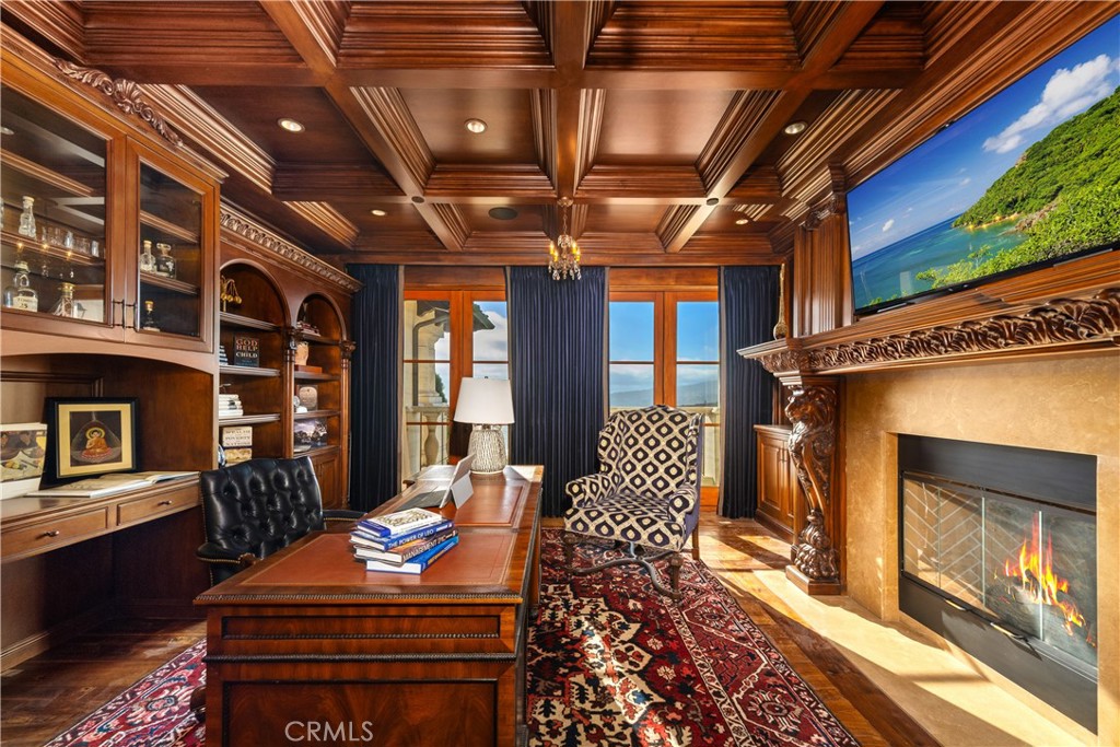 Furnished wood-paneled office with a coffered ceiling, carved fireplace, and ocean views.