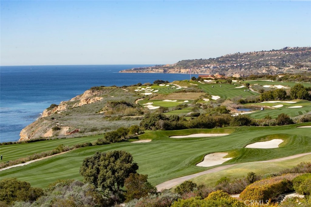 Coastal golf course with rolling fairways, sand bunkers, and the Pacific Ocean beyond.