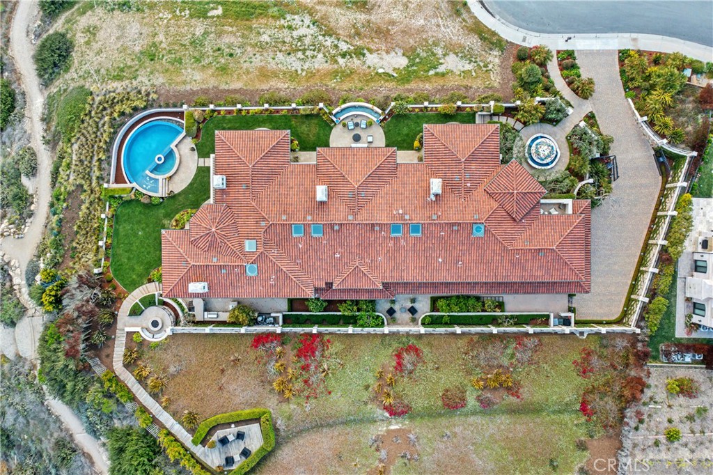 Aerial view of a large red-tile-roof home with a curved pool and landscaped grounds.