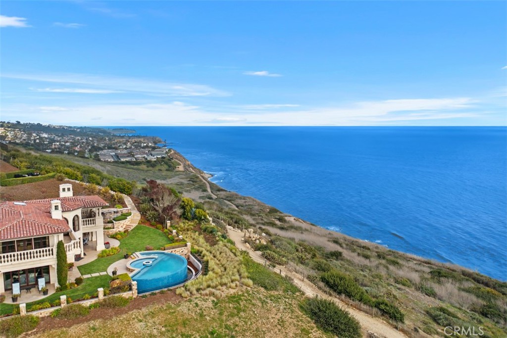 Coastal home with a curved pool overlooking oceanfront cliffs and the Pacific Ocean.