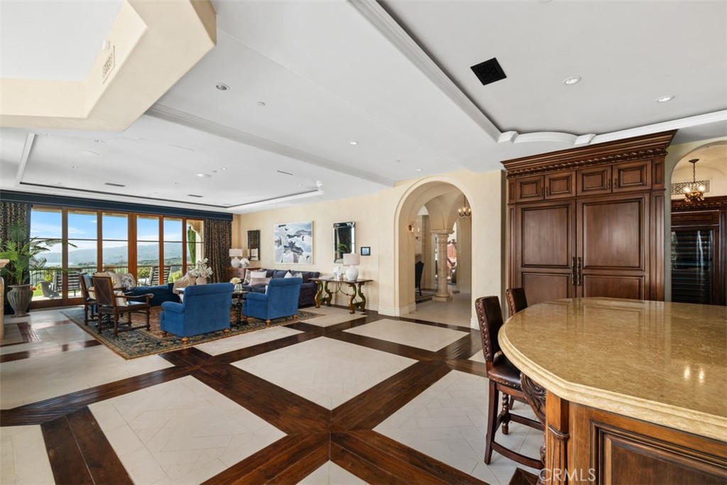 Living room and dining area with blue seating, a carved wood bar, and large windows.