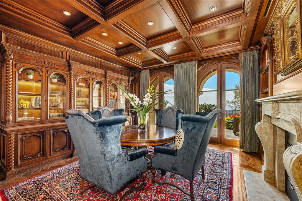Formal dining room with ornate wood cabinetry, a coffered ceiling, and arched glass doors.