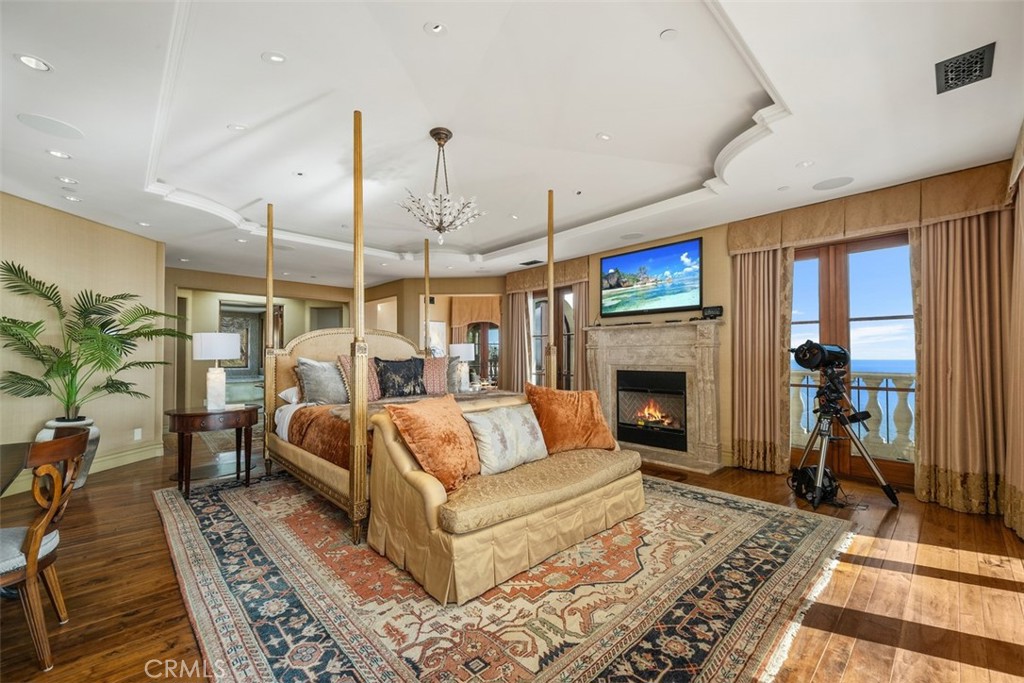 Bedroom with a four-poster bed, fireplace, and ocean views through glass doors.