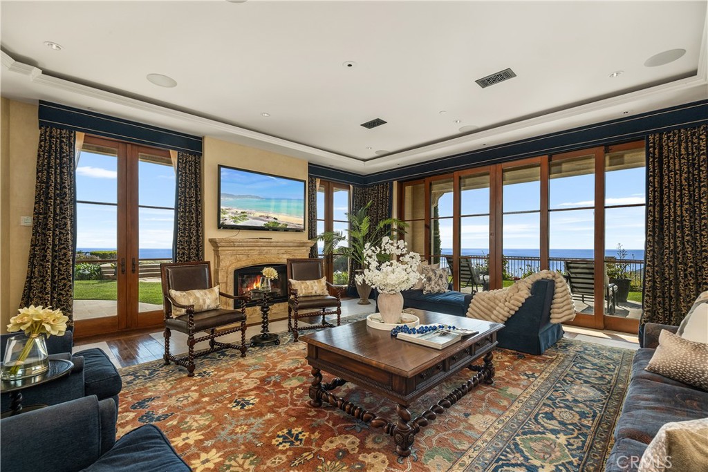 Living room with a stone fireplace, tall ocean-facing windows, and a balcony view.