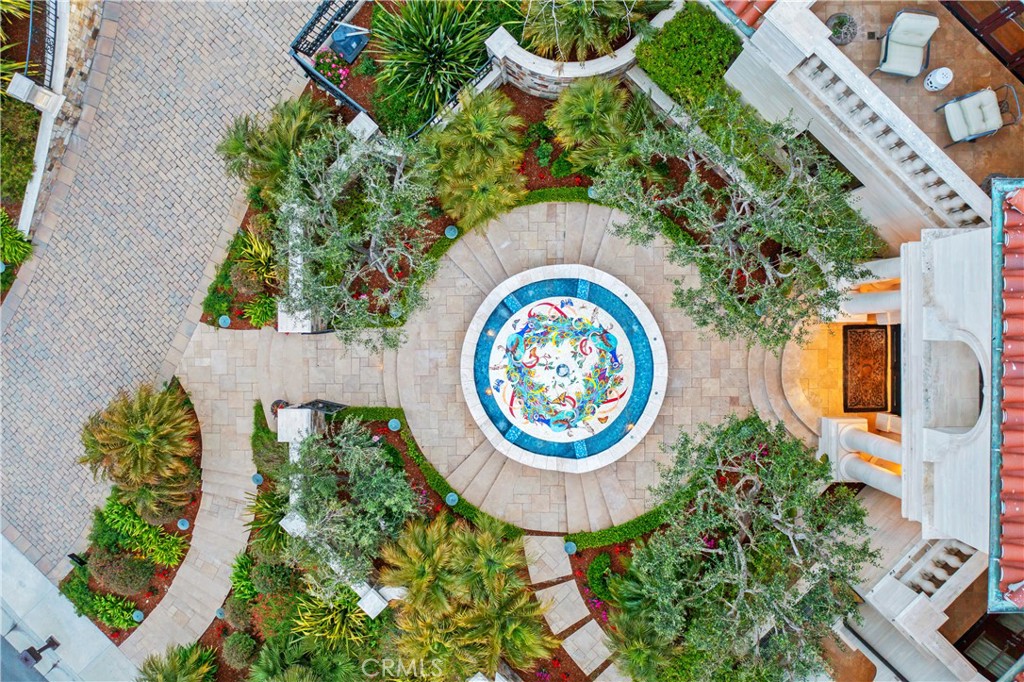 Aerial courtyard with a colorful circular mosaic fountain surrounded by stone paving and lush landscaping.