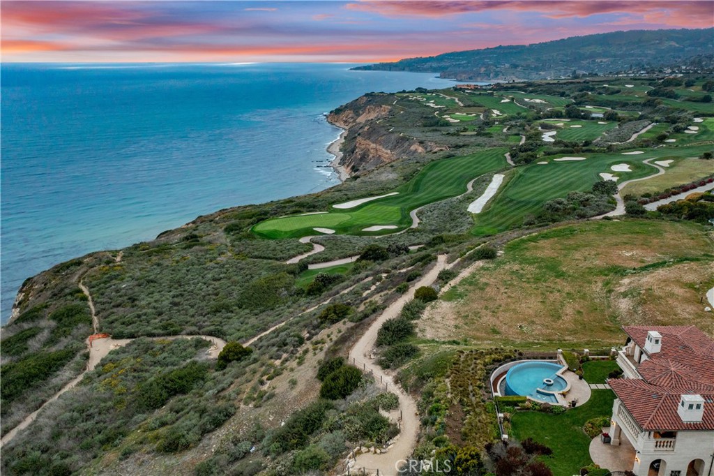 Coastal golf course beside the ocean, with a home and pool in the foreground.