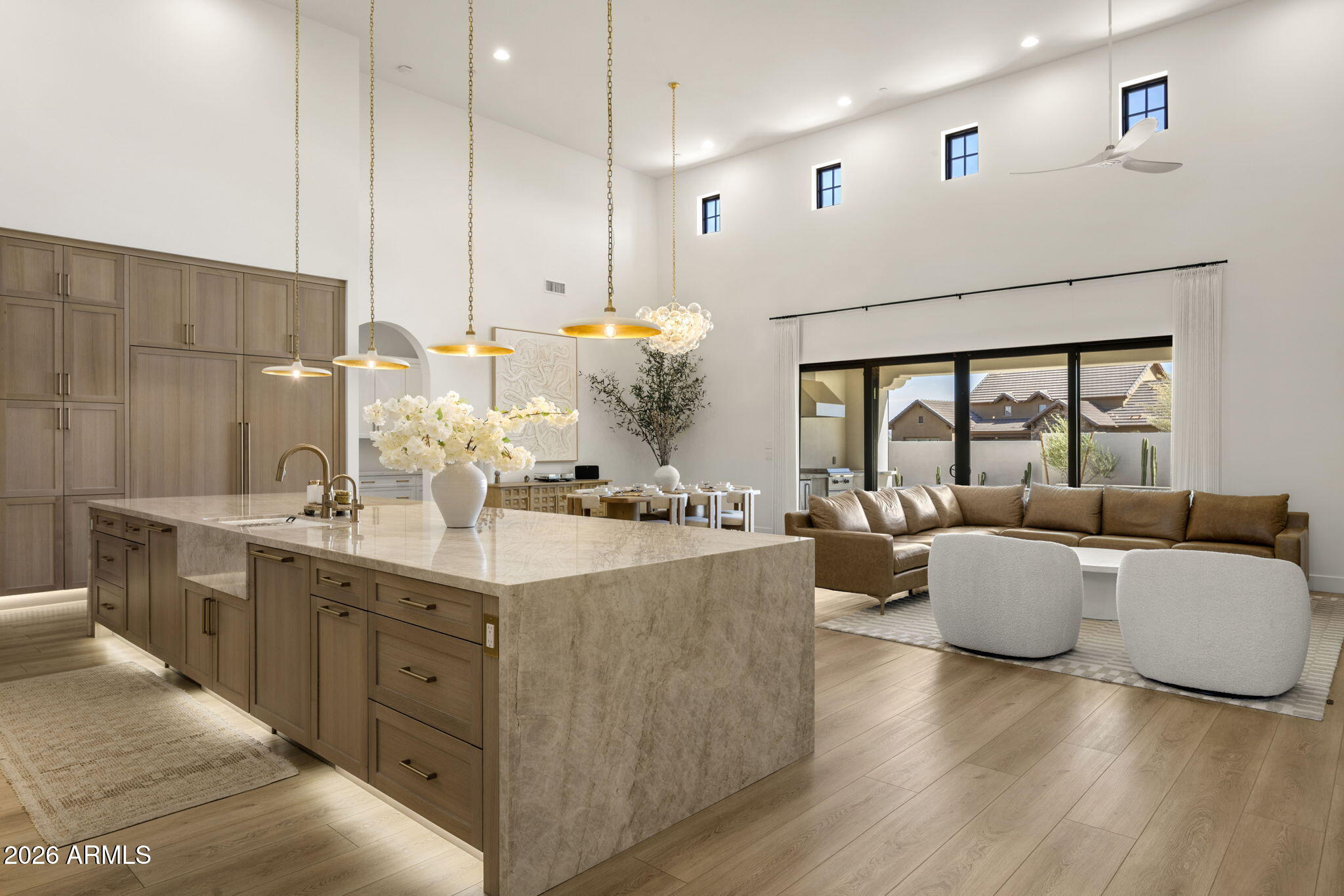 Open-plan kitchen and living room with a large stone island, wood cabinetry, and vaulted ceiling.