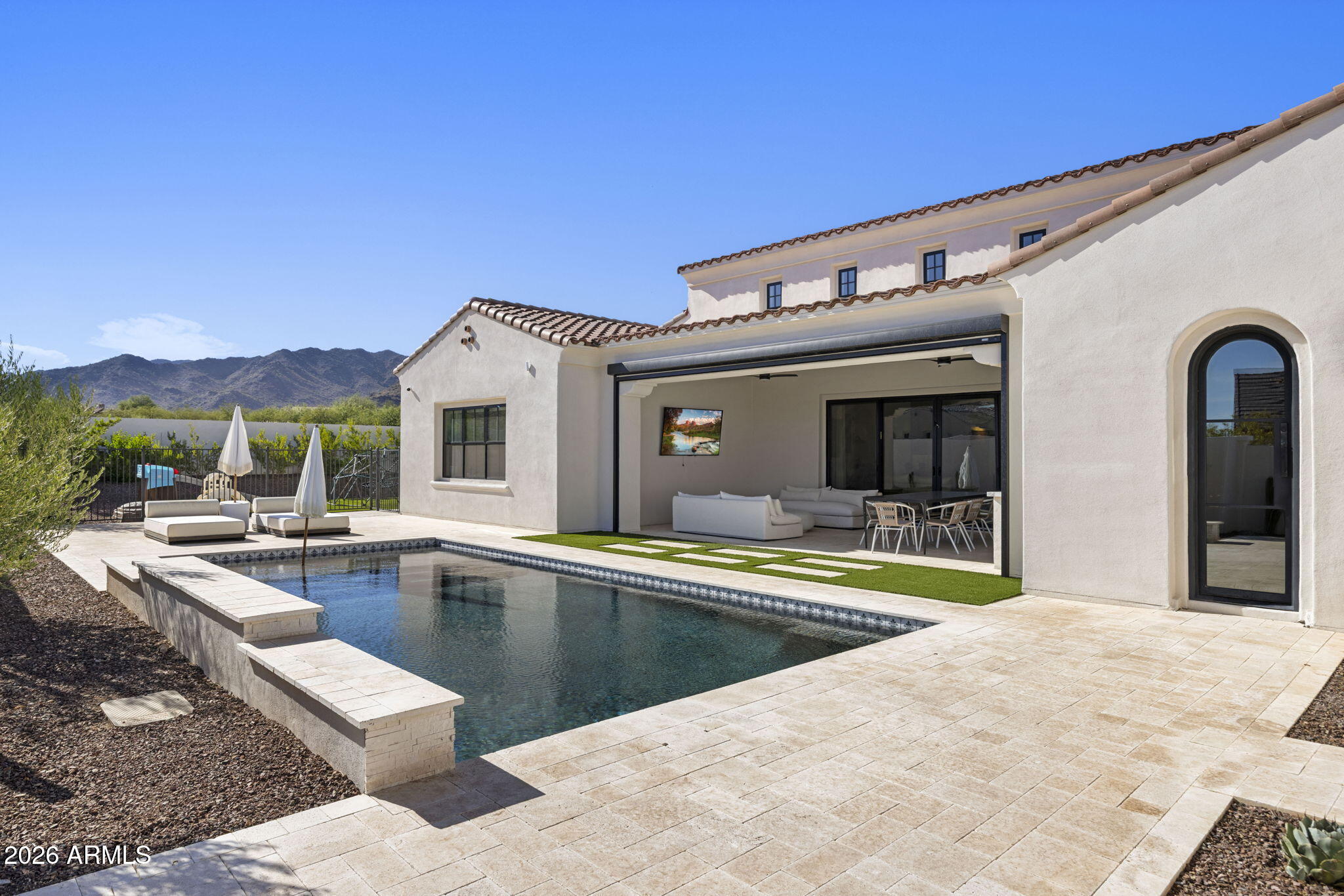 Home exterior with swimming pool, covered furnished patio, and mountain views.