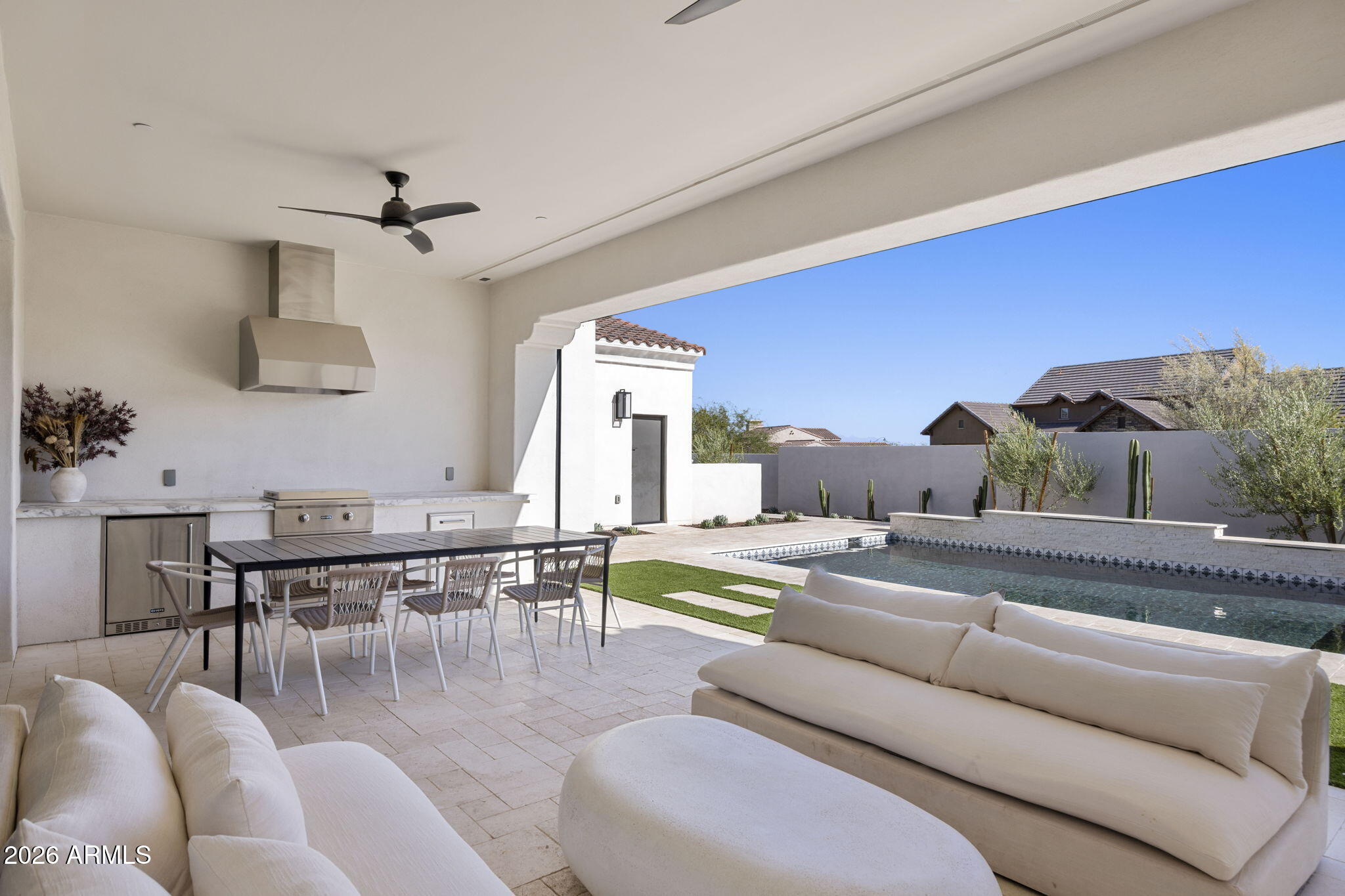 Covered patio with an outdoor kitchen, lounge seating, and pool.