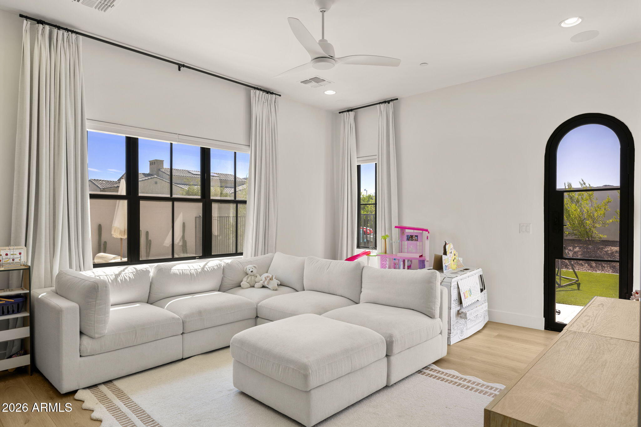 Living room with a white sectional sofa, tall windows, and an arched glass door to the yard.