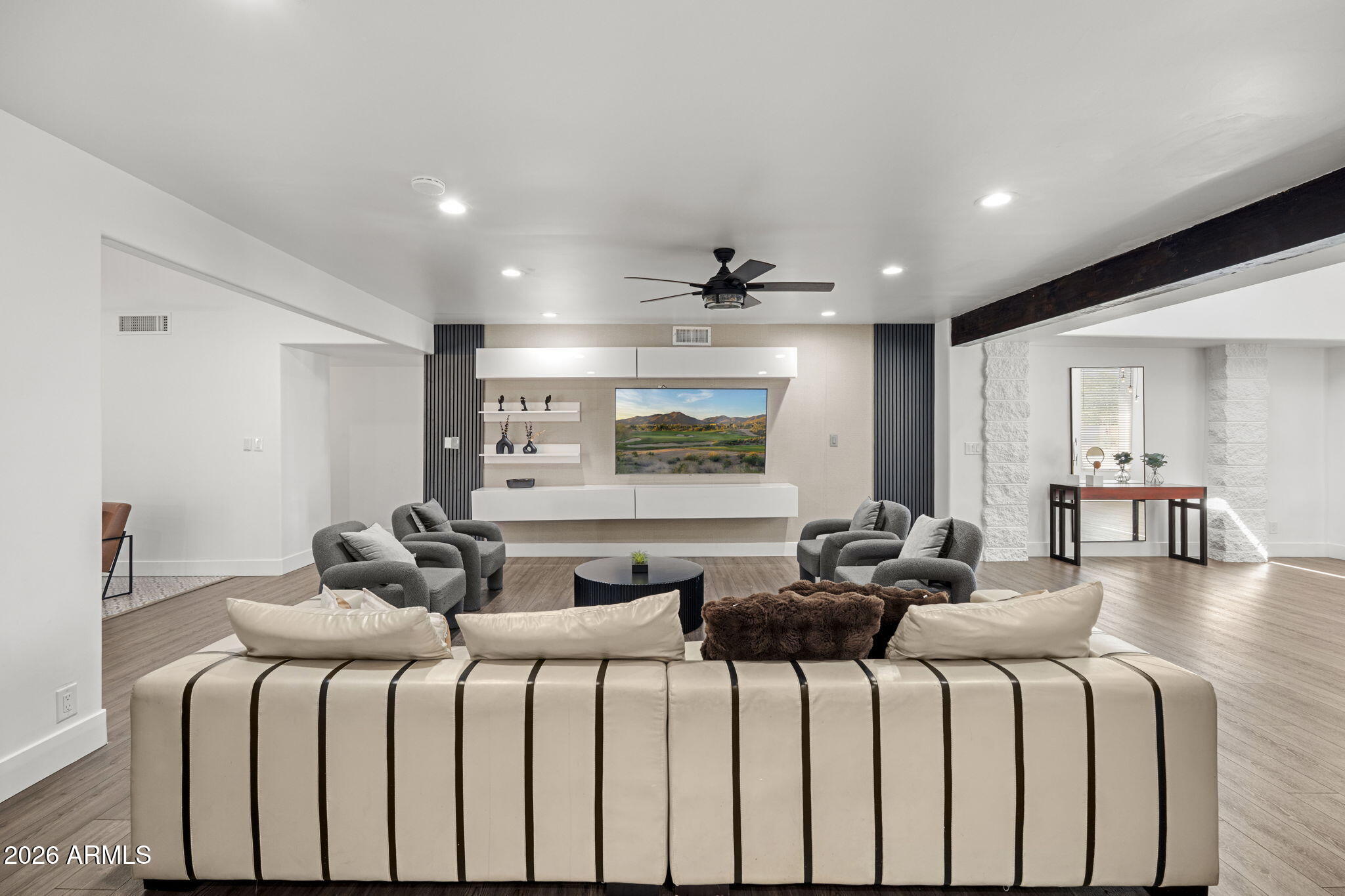 Living room with striped cream sofa, gray lounge chairs, and a built-in media wall.
