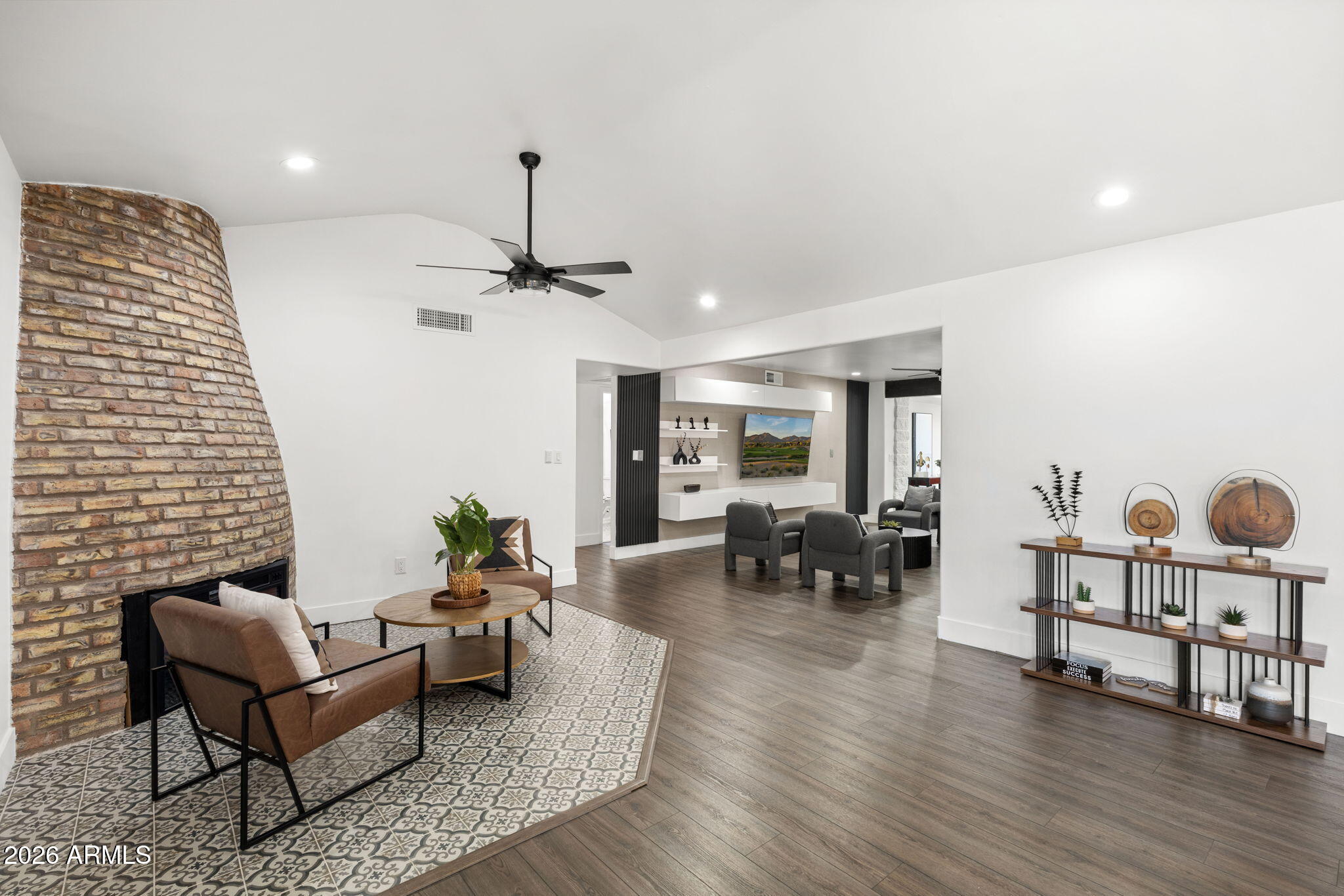 Living room with a curved brick fireplace, patterned tile hearth, and open adjoining sitting area.