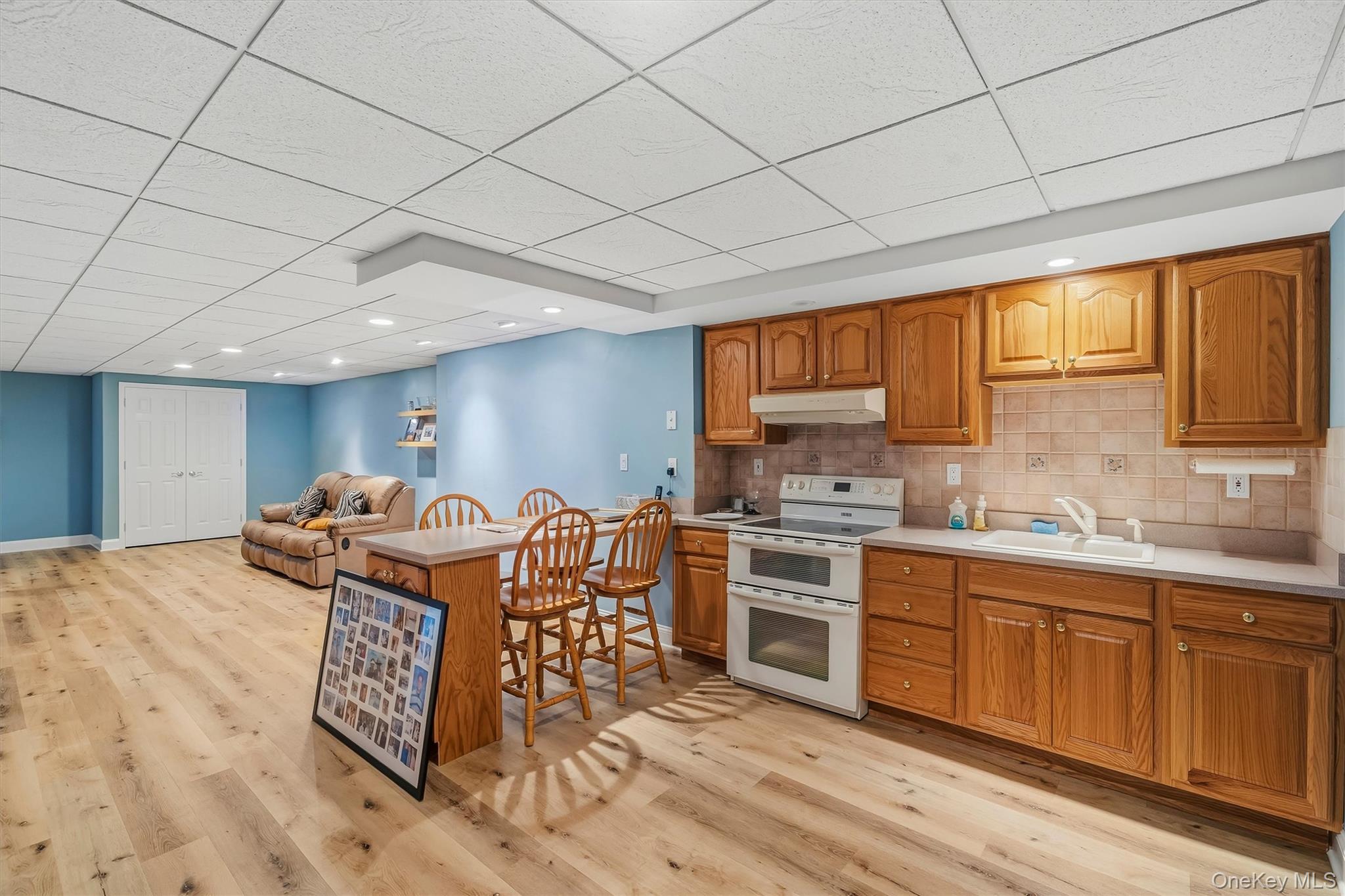 Kitchen with wood cabinetry and dining island, opening to a blue-walled sitting area.
