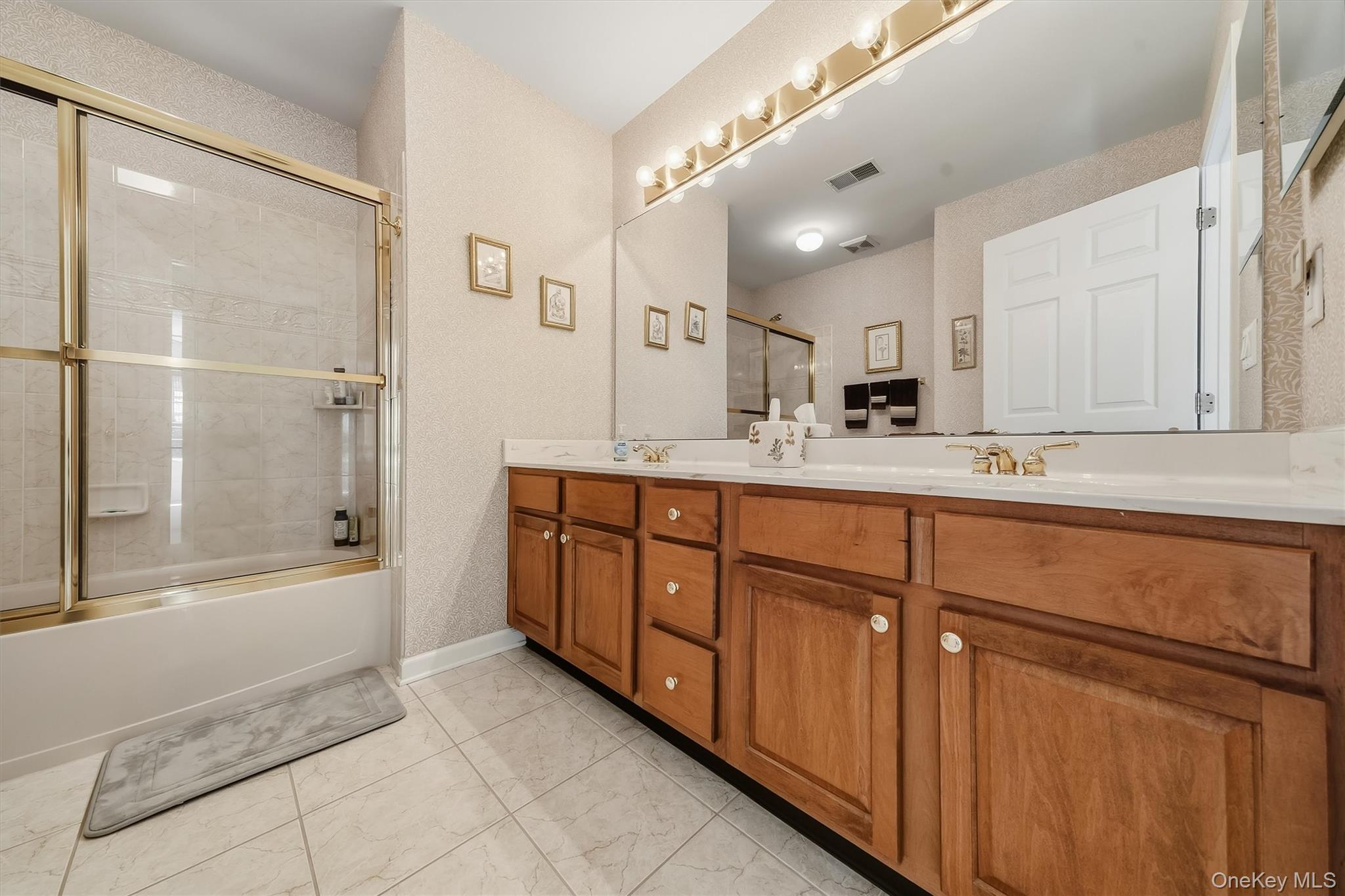 Bathroom with a glass-enclosed tub and shower beside a long wood double-sink vanity.