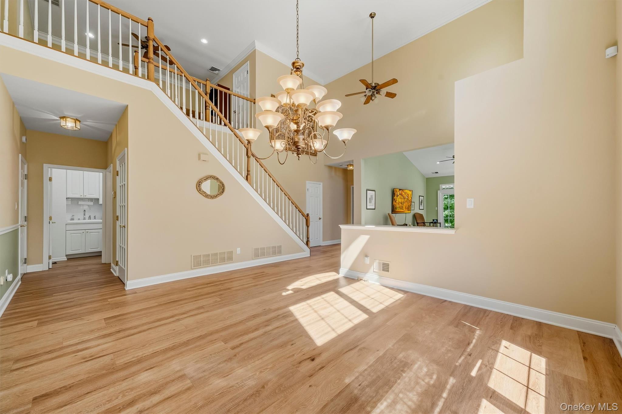 Two-story foyer with hardwood floors, a sweeping staircase, and a large chandelier.