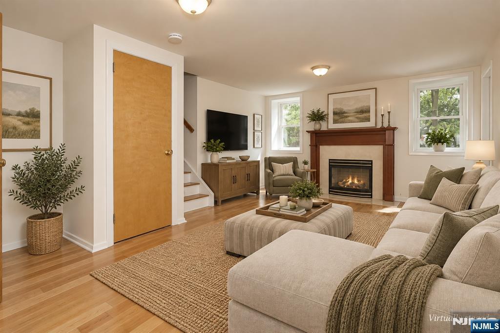 Staged living room with a beige sectional, woven rug, and lit fireplace.