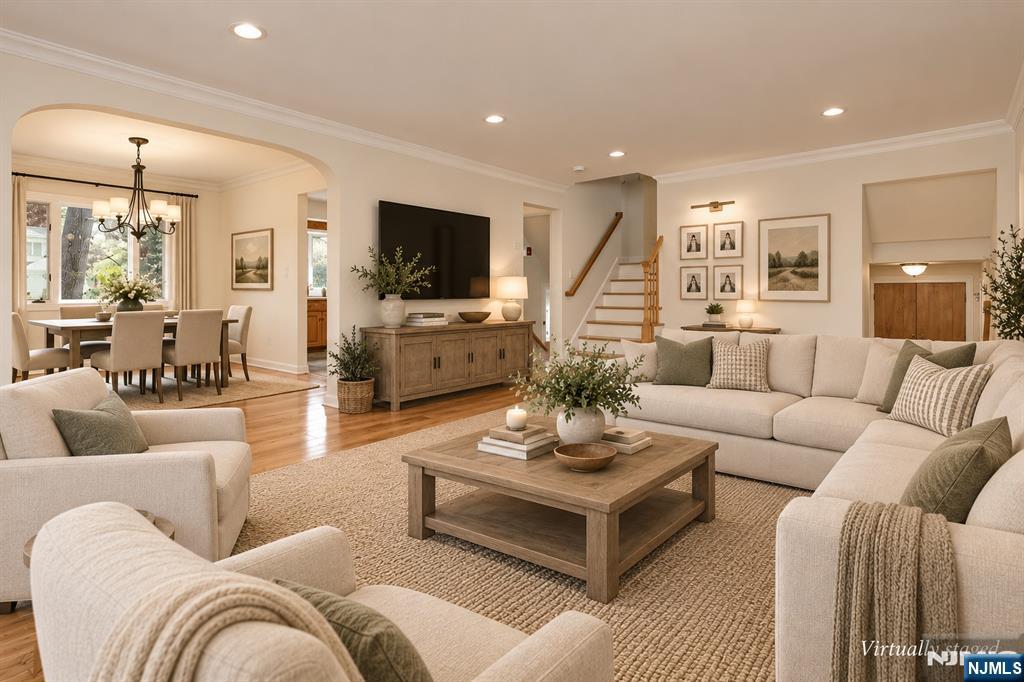 Staged living room with cream sofas, a wood coffee table, and an adjoining dining area.