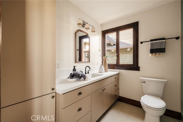 Bathroom with a long light vanity, dark-framed window, toilet, and striped towel.