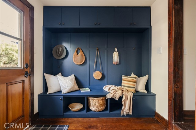 Entryway with a navy built-in bench, overhead cabinets, hooks, and woven storage baskets.