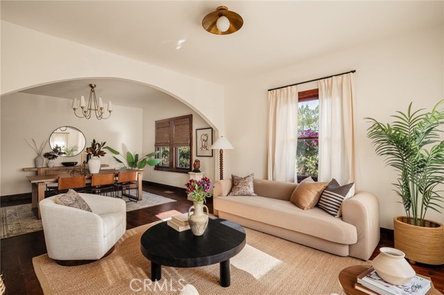 Living room with an arched opening to the dining area, a beige sofa, and a round black coffee table.