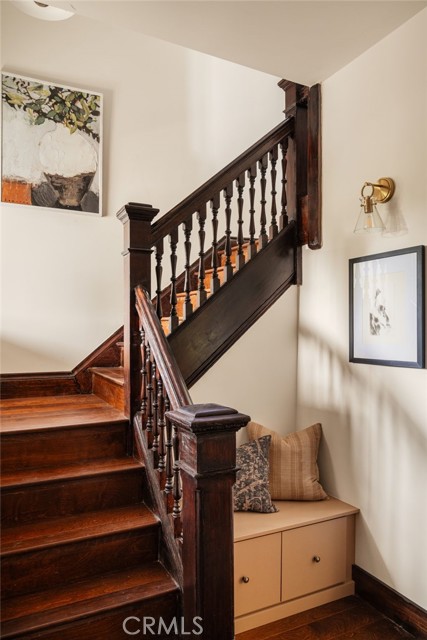 Dark wood staircase beside a built-in bench with cushions and framed artwork.