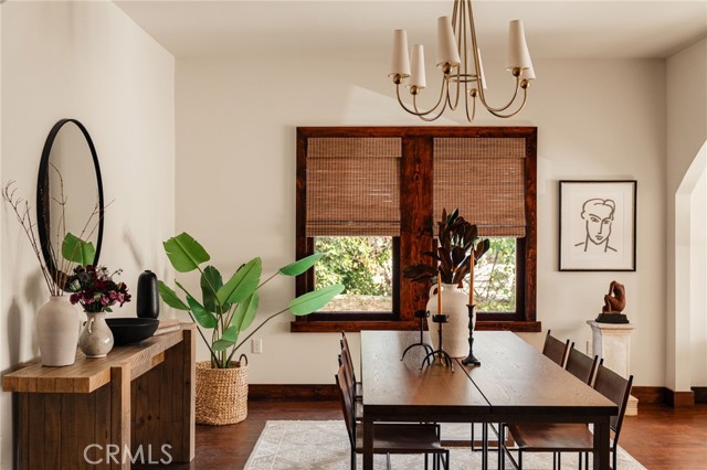 Dining room with a dark wood table, woven window shades, and a chandelier.