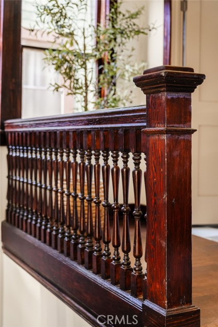 Dark stained wood staircase railing with turned balusters and a large square newel post.