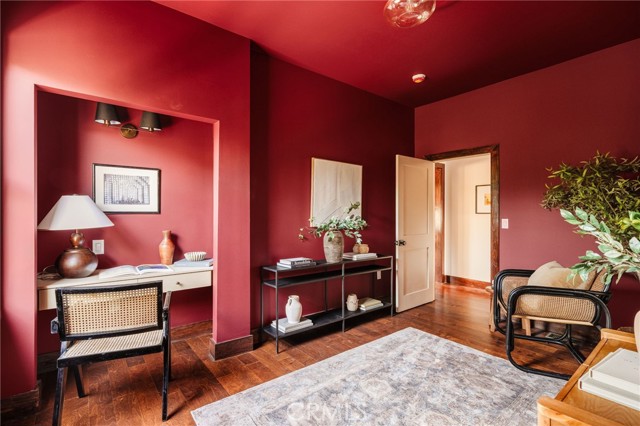 Red-walled room with a built-in desk nook, wood floors, and cane seating.