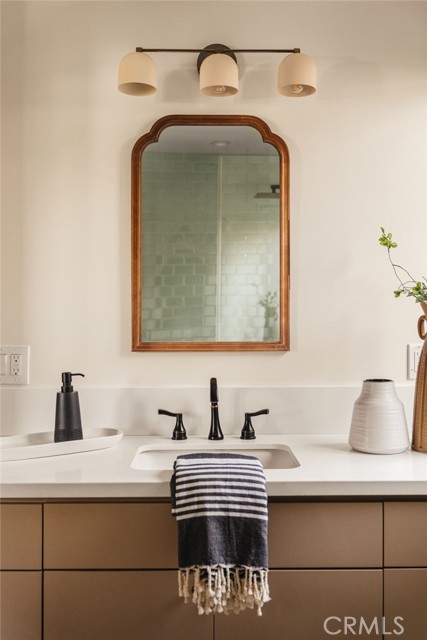 Bathroom vanity with a wood-framed mirror, black faucet, and striped towel.