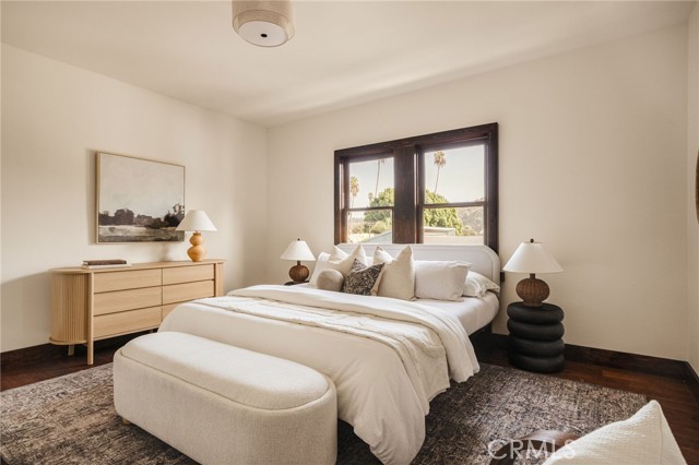 Bedroom with a large upholstered bed, neutral bedding, a window, and a light wood dresser.