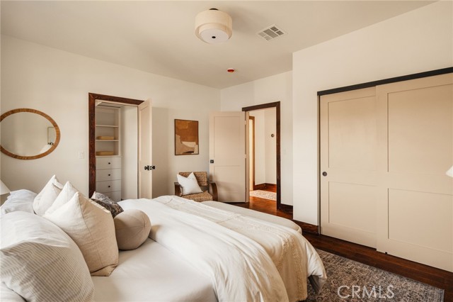 Bedroom with white bedding, a round wall mirror, and wide sliding closet doors.