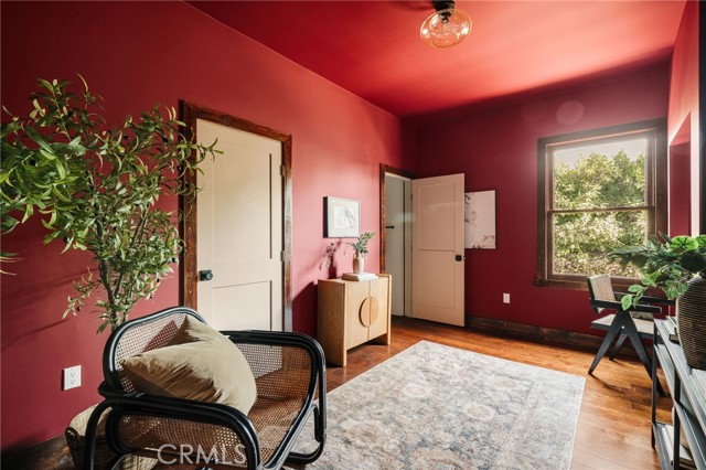 Furnished interior with deep red walls, hardwood floors, and a large sunlit window.