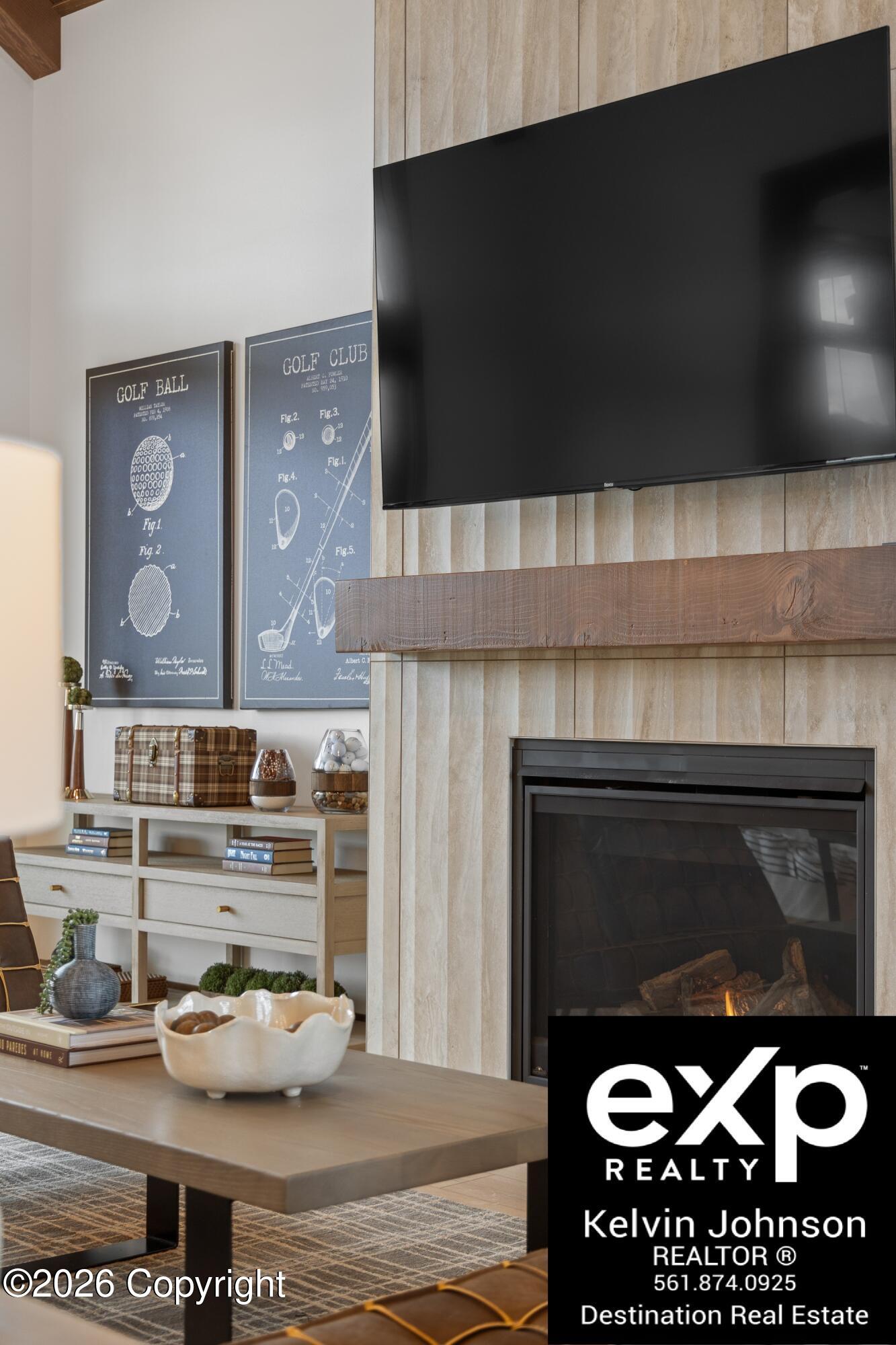 Furnished living room with a television above a stone fireplace and golf-themed wall prints.