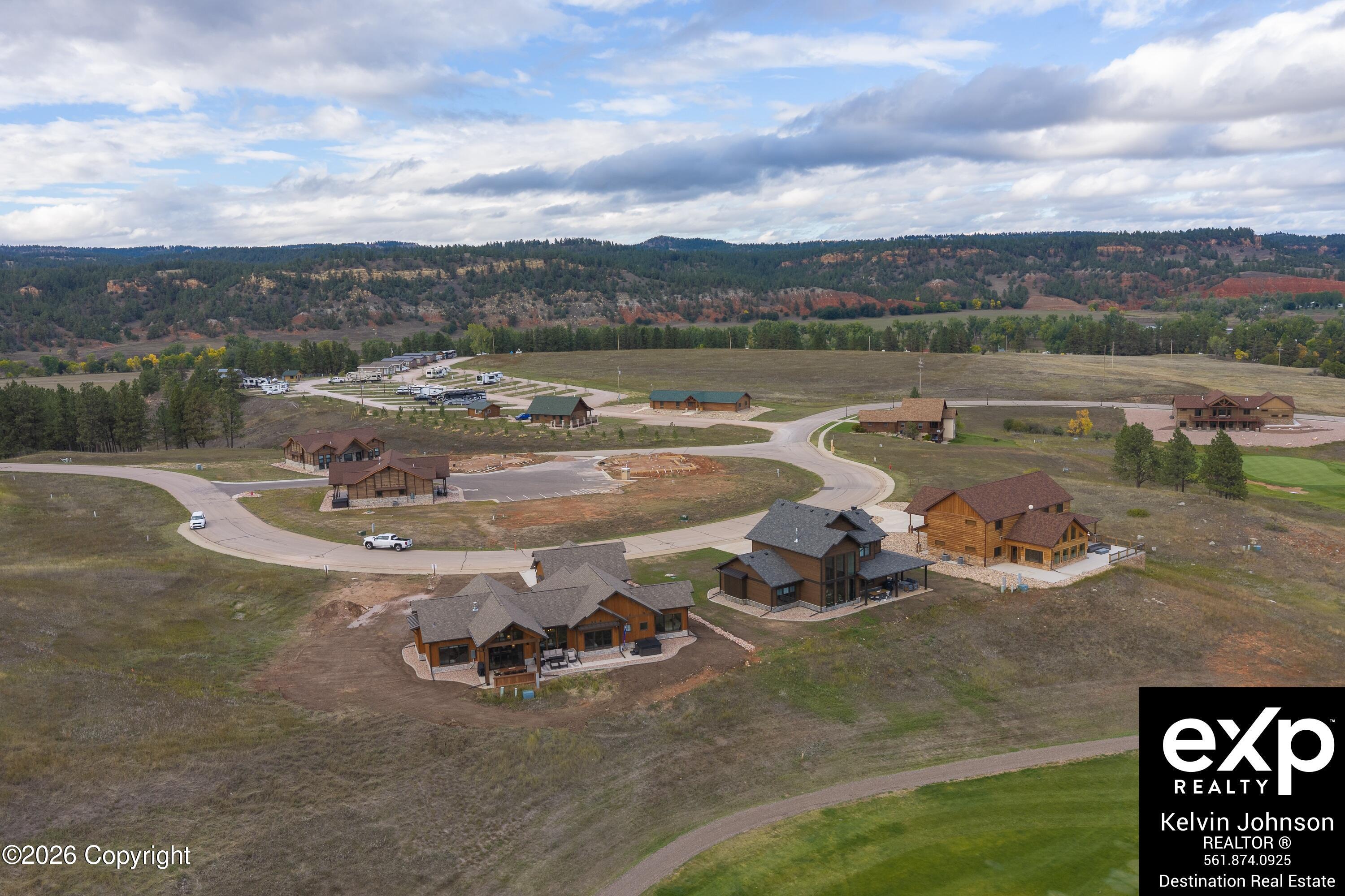 Aerial view of a residential development with modern homes, curving roads, and forested rocky ridges.