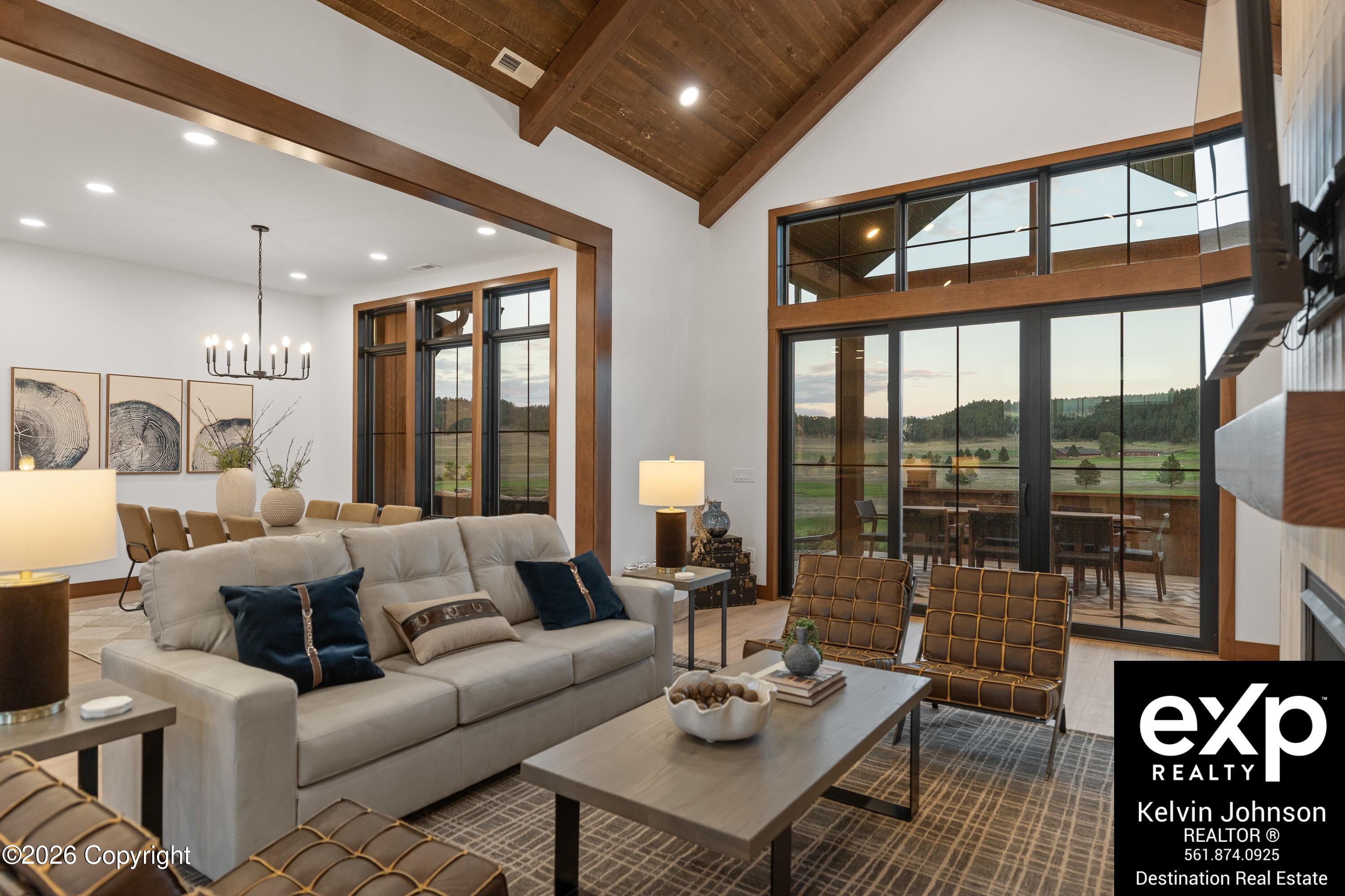 Furnished living room with a vaulted wood ceiling, large glass doors, and views of the countryside.