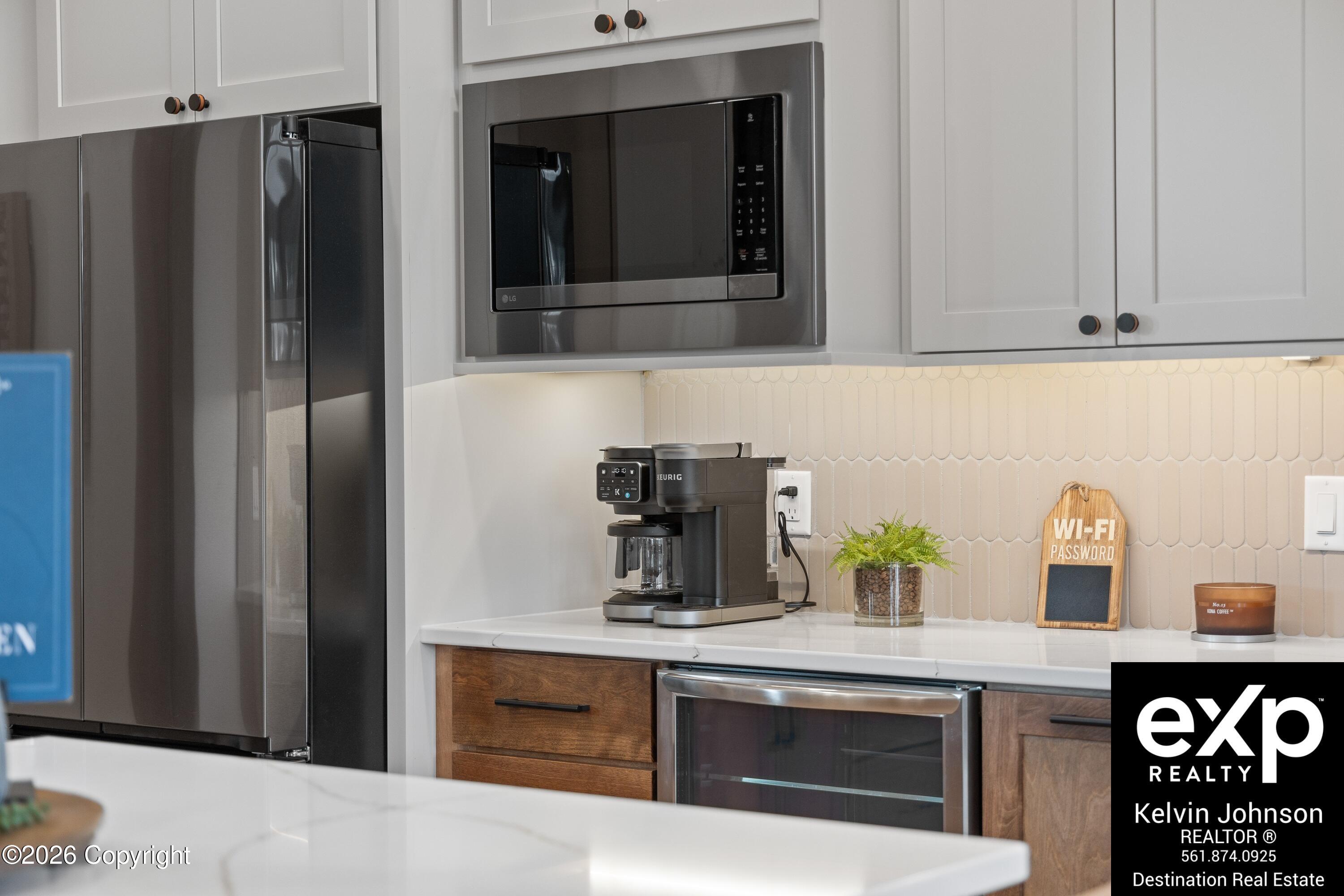 Kitchen with stainless-steel appliances, pale tile backsplash, and a coffee station on the counter.