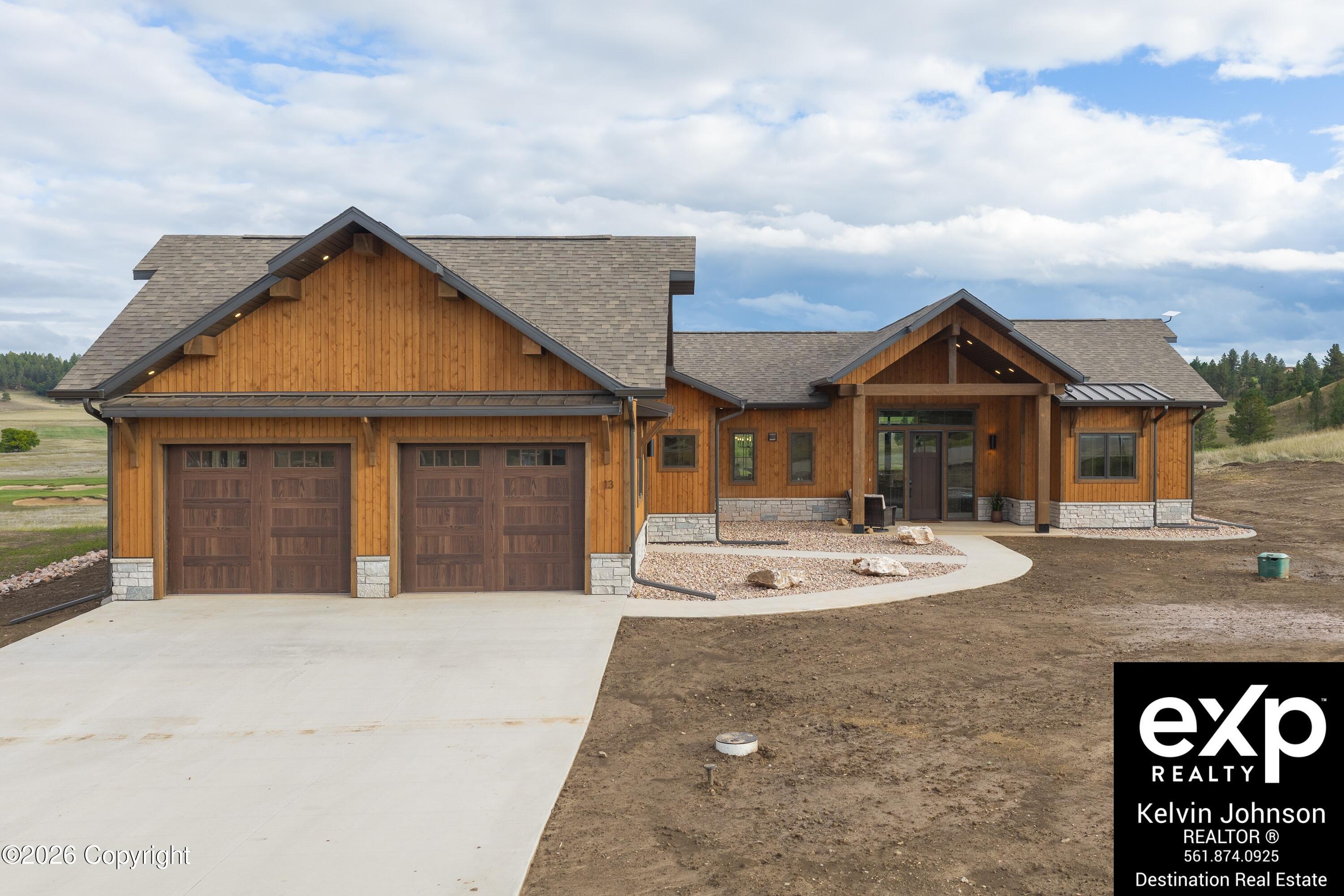 Wood-sided home with stone accents, a two-car garage, and a covered front entry.