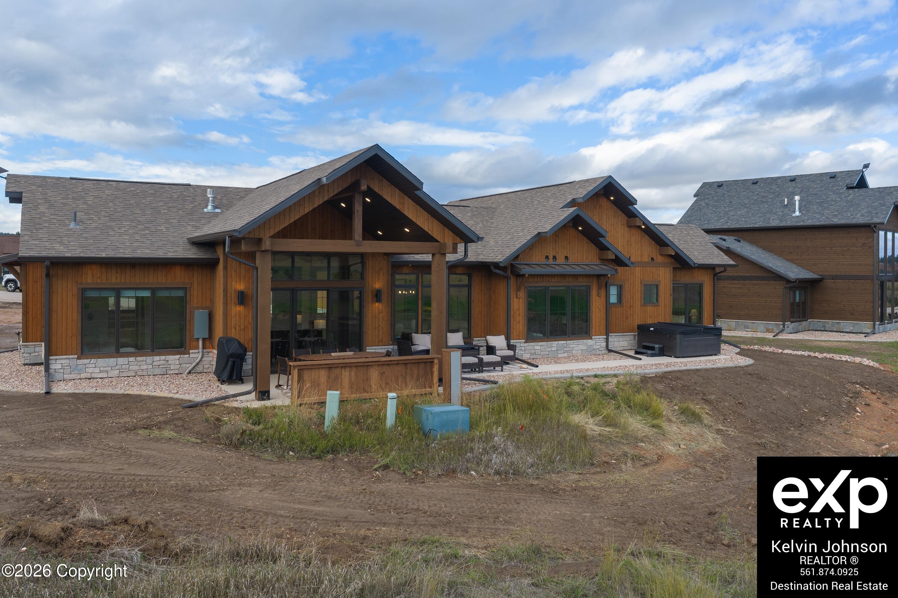 Wood-sided home with a covered patio, outdoor seating, and a hot tub.